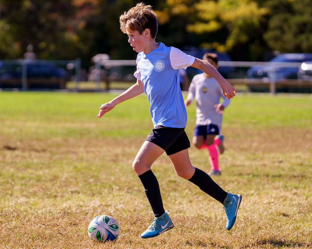 Young North Fork United player dribbling during a match
